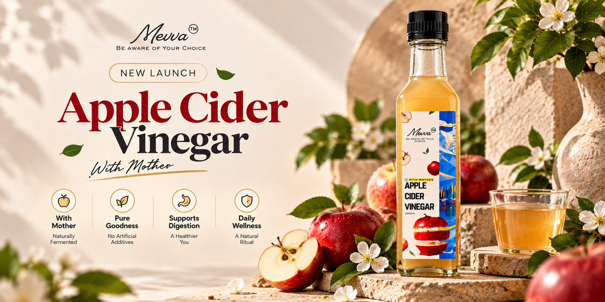 Mevva apple cider vinegar with Mother, a new launch, in a glass bottle beside fresh red apples on a stone platform
